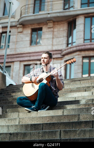 Casual man playing on the guitar outdoors Stock Photo