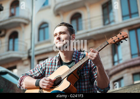 Happy man playing on guitar outdoors Stock Photo
