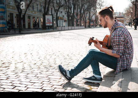 Man playing on the guitar outdoors in old city Stock Photo