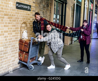 Harry Potter fans posing at the fictional platform 9 & 3/4, Kings Cross Railway Station, London, England. Stock Photo