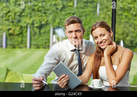 Happy student couple working with tablet computer at a table in a coffee shop Stock Photo
