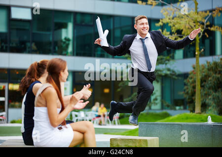 Brave businessman jumping over obstacle in front of his team members Stock Photo
