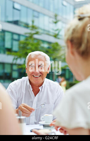 Old businessman sitting with a cup of espresso in a coffee shop Stock Photo