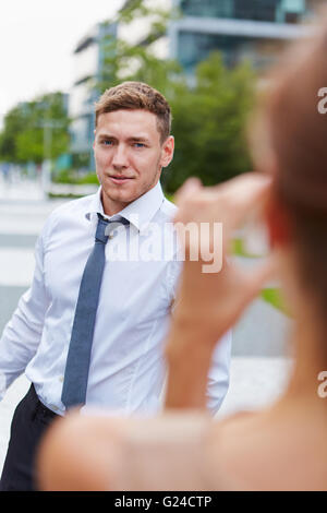 Young woman taking pictures of business man with smartphone in the city Stock Photo