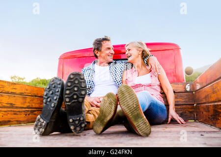 Senior couple sitting in back of red pickup truck Stock Photo