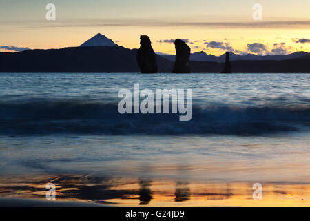 A beautiful sunset - picturesque view of Three Brothers Rocks in Avacha Bay and Vilyuchinsky Volcano on the horizon. Russian Far East, Kamchatka Stock Photo