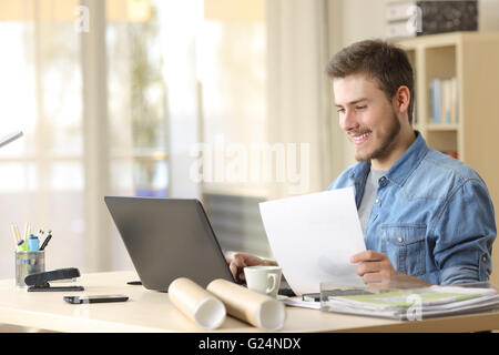 Entrepreneur working with a laptop and holding a document in a little office or home Stock Photo