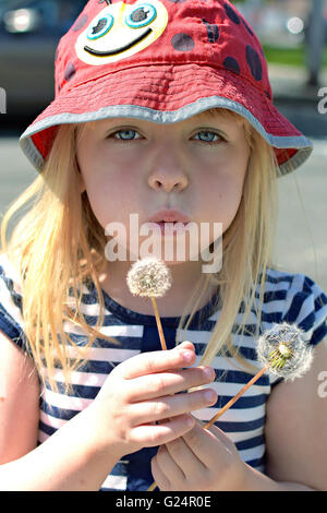 young girl blowing dandelion in springtime Stock Photo