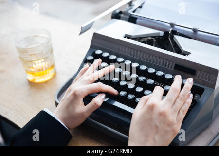 Woman's hands writing on old typewriter over wooden table background Stock Photo