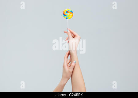 Closeup portrait of female arms holding lollipop on stick isolated on a white background Stock Photo