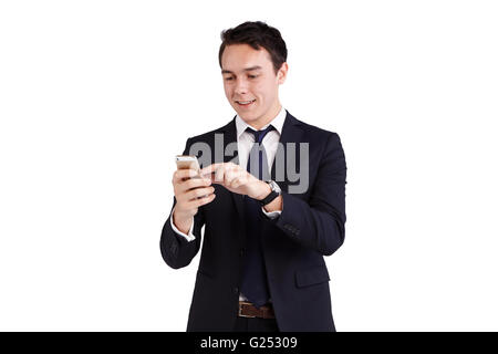 A young Caucasian business man is holding a mobile phone smiling. He is holding the smart phone on one hand and operating with a Stock Photo