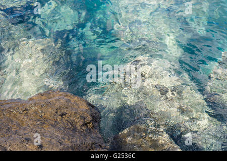 Defocused image of rock and transparent turquoise water, ripple on surface Stock Photo