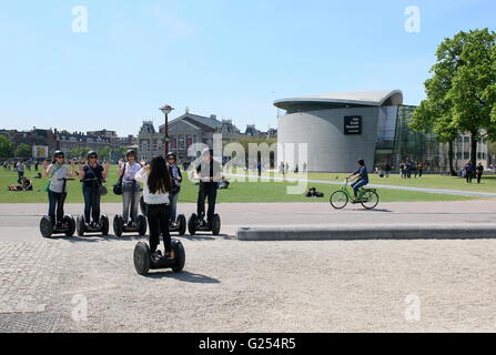 Tourists on Segways at Museumplein (Museum Square), Amsterdam, Netherlands In background the Concert Hall & Van Gogh Museum. Stock Photo