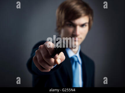 Stressed businessman holding and pointing a gun to the camera Stock Photo