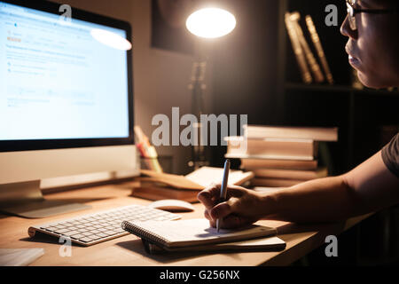 Closeup of handsome asian young man sitting and studying with computer at home at nighttime Stock Photo