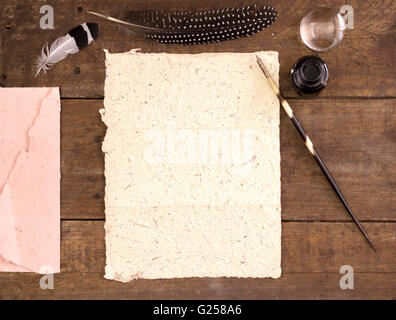 Blank letter paper, envelope and quill pen with ink pot and feathers on wood desk table Stock Photo
