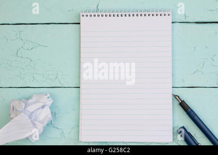 Fountain pen and blank paper note pad on turquoise rustic wood table with pen and crumpled paper Stock Photo