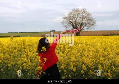 Woman waving scarf in rapeseed field, Niort, France Stock Photo