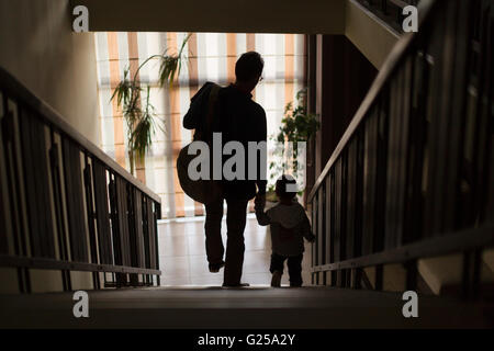 Father and son walking down stairs holding hands Stock Photo