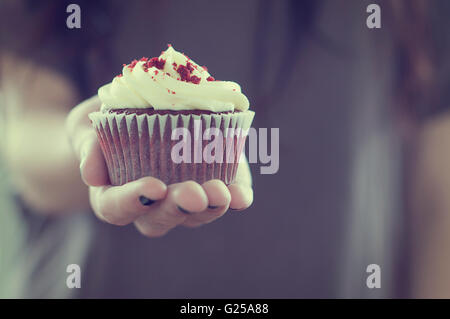 Teenage girl holding a red velvet cupcake