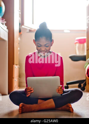 Girl sitting on floor with her digital tablet Stock Photo