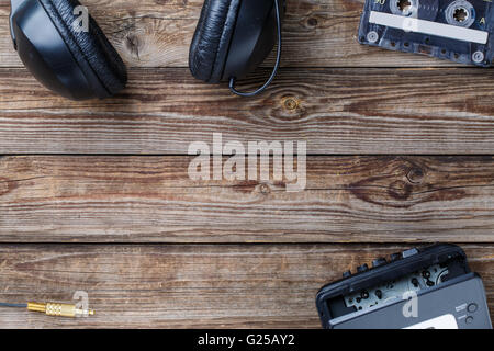 Cassette tapes, cassette player and headphones over wooden table. top view. Stock Photo