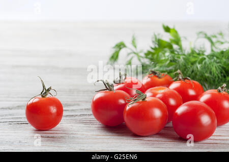 Cherry tomatoes and green dill on a wooden table Stock Photo