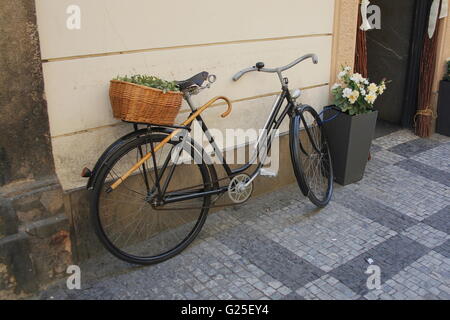 Old bicycle with wicker basket on the street Stock Photo