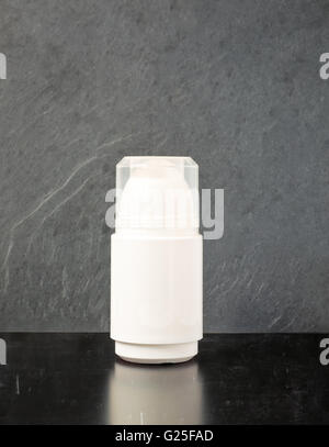 White roll on deodorant on a dark table with slate gray background. Stock Photo