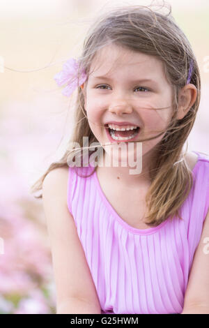 Pretty young girl in pink laughing in garden Stock Photo