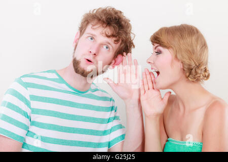 Closeup woman telling an astonished surprised man some secrets, couple talking Stock Photo