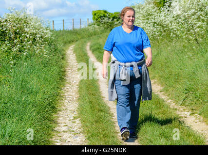 Weight loss. Middle aged woman walking along a country path in the summer.Healthy living. Healthy lifestyle. Getting fitter. Keeping fit. Stock Photo