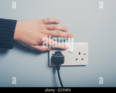 A male hand is pushing a switch on a wall socket Stock Photo