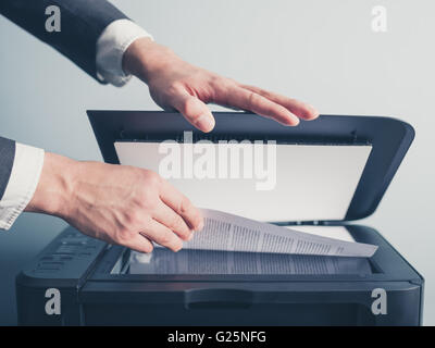 The hands of a young businessman is placing a document on a flatbed scanner in preparation for copying it Stock Photo