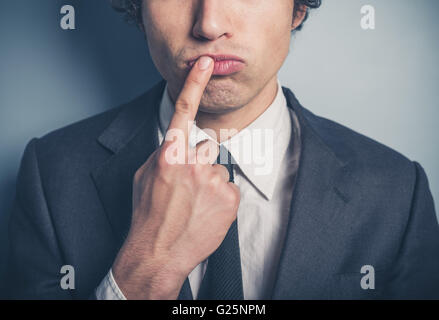 A thoughtful young businessman with his finger on his lips Stock Photo