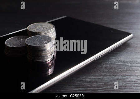 Stack of rupiah coin on smartphone showing it relation. Like business, money making, Stock Photo