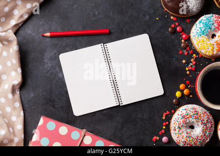 Notepad, donuts and coffee on stone table. Top view with copy space Stock Photo