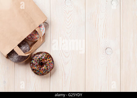 Donuts in paper bag on wooden table. Top view with copy space Stock Photo