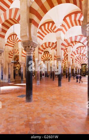 Columns at the Mezquita-Cathedral of Cordoba, Spain. Visitors walking around and taking photos. Stock Photo