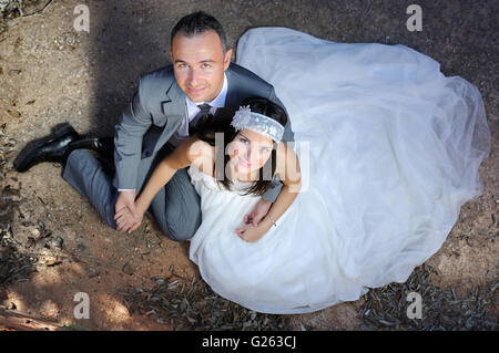 Groom and bride holding hands sitting on the floor Stock Photo