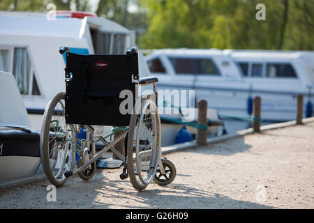 Wheelchair parked beside moored motor cruiser at Wroxham Stock Photo