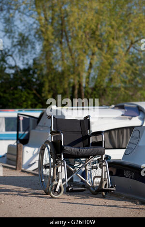 Wheelchair parked beside moored motor cruiser at Wroxham Stock Photo