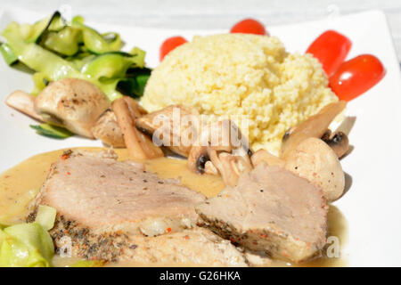 Baked pork loin with vegetables and mushrooms close-up on a baking ...