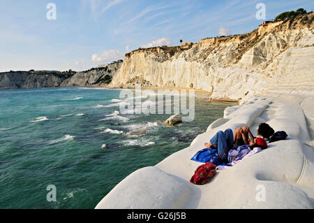 Two young women relaxing on the beautiful white marl cliff of the Scala dei Turchi, Realmonte, Sicily, Italy Stock Photo