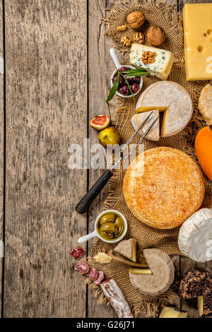 Various kind of traditional cheese and delicacy suitable for wine, placed on wood, shot from high angle view. Stock Photo