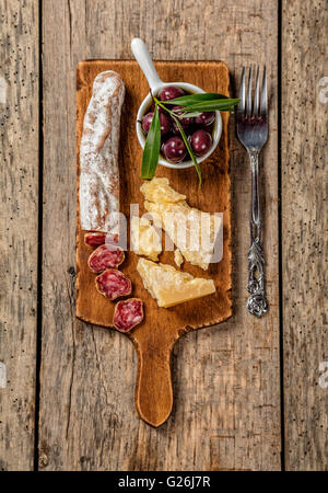 Various kind of traditional cheese and delicacy suitable for wine, placed on wooden cutting board, shot from high angle view. Stock Photo