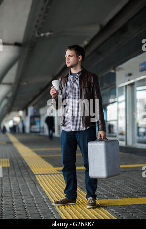 Young attractive man drinking coffee on his way near the airport terminal looking to the camera Stock Photo