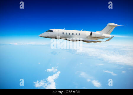 Luxury private jet plane flying above clouds in day light Stock Photo