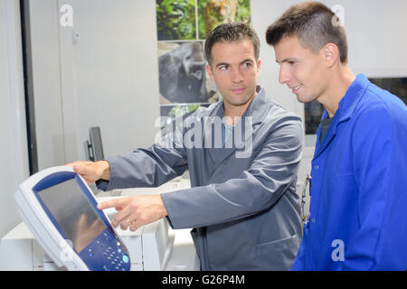 Man showing electronic control panel to apprentice Stock Photo
