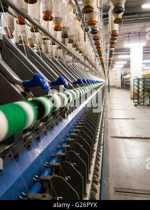 Production heads called spindles on textile spinning frame with individual threads yarns visible in infinite perspective Stock Photo